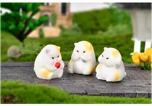 Vue détaillée de trois figurines de chat dodu en résine dans une scène de mini jardin.
