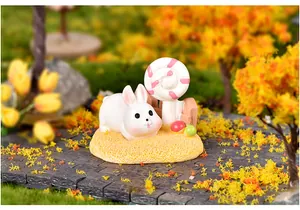 Gros plan d'une figurine de lapin en résine avec sucette dans un jardin d'automne