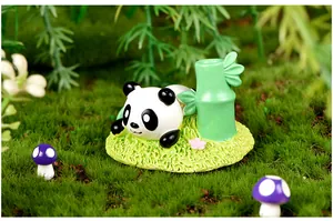 Gros plan d'une figurine de panda en résine dans un micro-paysage de mousse verte