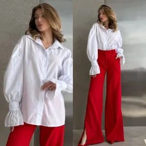 Close-up of white oversized shirt with puff sleeves and vibrant red wide-leg trousers set