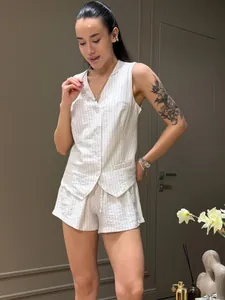 Modello indossa un gilet senza maniche gessato e pantaloncini set estivo casual.