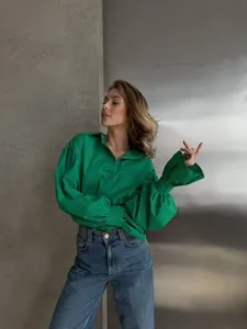 Stylish woman wearing a bright green oversized shirt with puff sleeves and denim jeans