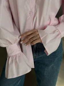 Detailed view of a pink long-sleeve blouse with elegant ruffled cuffs and buttons