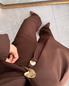 Primer plano de traje marrón de mujer con botones metálicos dorados en forma de corazón