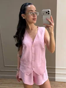 Dettaglio di un elegante set gilet rosa senza maniche e pantaloncini in selfie.