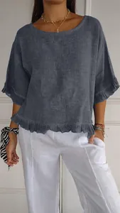 Detalle de una blusa de lino de manga corta en azul grisáceo con volantes y cuello redondo.