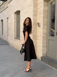 Elegant solid black short-sleeve midi dress with cinched waist shown in lifestyle setting