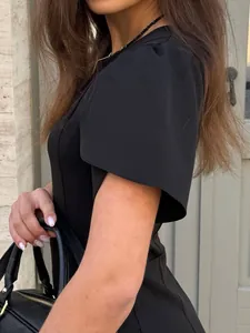 Close-up detail of a elegant black dress with flutter sleeves and textured fabric.