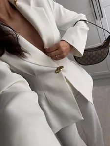 Elegante traje de chaqueta blanca entallada para mujer con botón dorado, look chic.