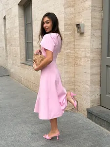 Outdoor full-length view of an elegant pink short sleeve waisted dress with pleated shoulders