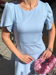 Close-up of light blue summer dress featuring elegant petal sleeves and a slim waist.