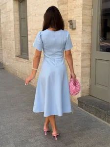Back view of elegant light blue short-sleeved dress with cinched waist and pleated skirt