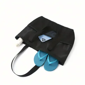 Close-up of a black mesh beach bag showing storage capacity with phone and blue flip-flops.