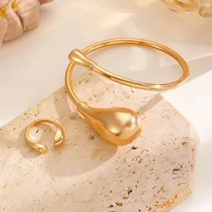 Detailansicht eines goldenen minimalistischen Tropfen-Chokers und Rings auf Stein.