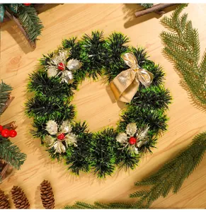 Vue détaillée d'une couronne de Noël avec guirlandes vertes, nœud doré et baies rouges