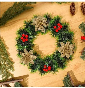 Vue détaillée d'une couronne de Noël verte avec des fleurs dorées et des baies rouges sur bois.