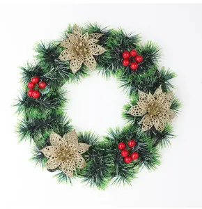 Détail d'une couronne de Noël artificielle avec guirlandes vertes, fleurs dorées et baies