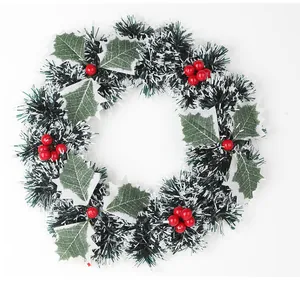 Gros plan d'une couronne de Noël artificielle avec des feuilles de houx et baies rouges.