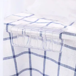 Vue rapprochée de pinces à nappe en plastique transparent fixant une nappe à carreaux