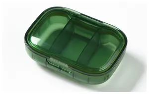 Macro view of a compact green translucent pill storage box with three compartments.