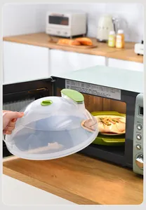 Close-up van een transparante magnetronafdekking die wordt gebruikt met een bord eten.