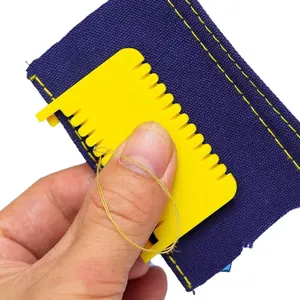Detail view of a yellow plastic sewing guide tool being used on dark blue fabric