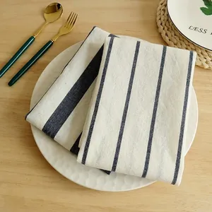 Vista detallada de paños de cocina de algodón a rayas azules y blancas en un plato blanco