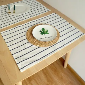 Detalle de mantel individual de algodón a rayas azules y blancas en mesa de madera