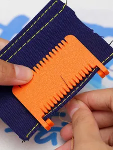 Close-up of orange plastic sewing tool positioner being used on blue fabric detail view