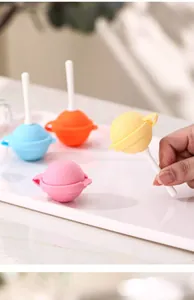 Hand holding a yellow planet-shaped silicone lollipop popsicle mold in pastel colors