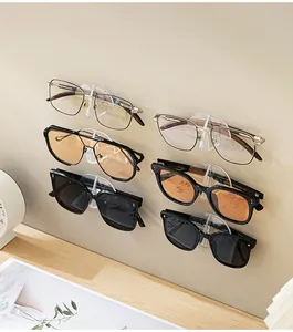 Wall-mounted clear adhesive organizer hooks holding multiple sunglasses on a minimalist wall