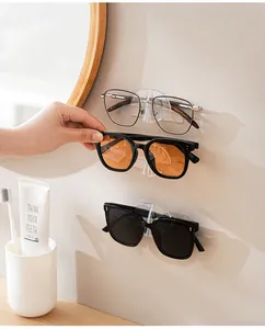 Wall-mounted transparent glasses storage rack holding sunglasses in a bathroom setting.