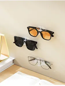Detail shot of wall-mounted clear glasses hooks holding various sunglasses above a desk