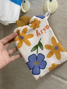 Detail eines verdickten Peeling-Badehandschuhs mit gelben und blauen Gänseblümchenmustern.