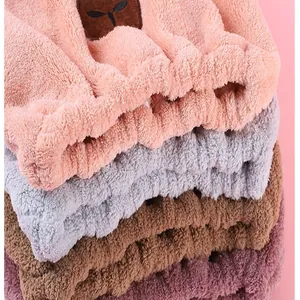 Close-up of stacked colorful coral fleece hair drying caps showing soft texture and bear detail