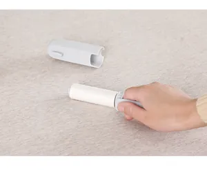 Dettaglio di un mini rullo levapelucchi portatile con coperchio grigio su stoffa beige.