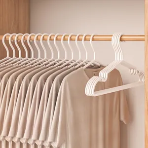 White minimalist non-slip clothes hangers with shoulder grooves holding shirts in a closet