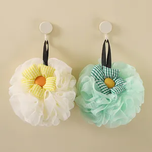 Decorative soft sunflower mesh bath sponges in white and light green hanging on hooks.