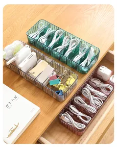 Detail view of multi-compartment plastic organizer box storing cables on a desk