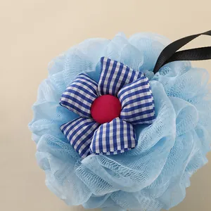 Close-up detail of a soft light blue flower bath loofah with a gingham fabric center