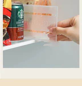 Primer plano de una mano ajustando un divisor de cajón de refrigerador ajustable.
