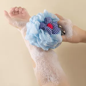 Soft blue mesh shower sponge with decorative flower detail in soapy use
