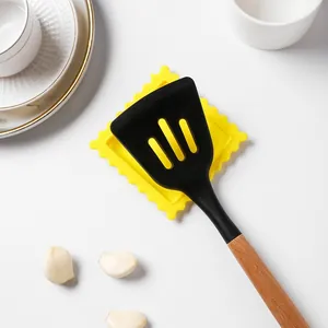 Primo piano di una spatola in silicone nero su un poggia cucchiaio a forma di biscotto.