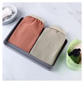 Detailed view of two coarse sand exfoliating bath mitts in red and beige tones