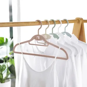 Set of multi-colored slim plastic hangers hanging white shirts on a wooden rack.