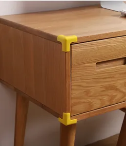 Soft yellow silicone corner protectors installed on a wooden desk for child safety.