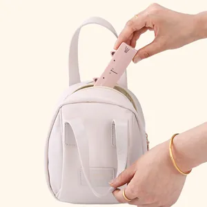 Portable pink cat-shaped washable lint roller being tucked into a small bag for travel