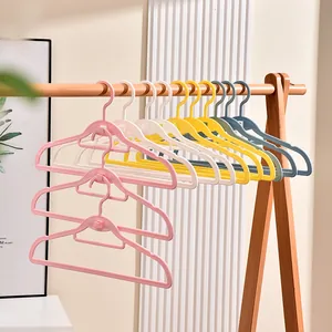 Bunte nahtlose Kunststoff-Kleiderbügel auf einem Holzständer für Haushaltswäsche.