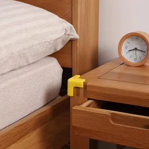 Yellow L-shaped baby safety corner guard protector installed on a wooden table corner