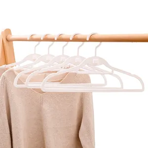 Set weißer nahtloser Kunststoff-Kleiderbügel an einer Holzstange mit beigem Pullover